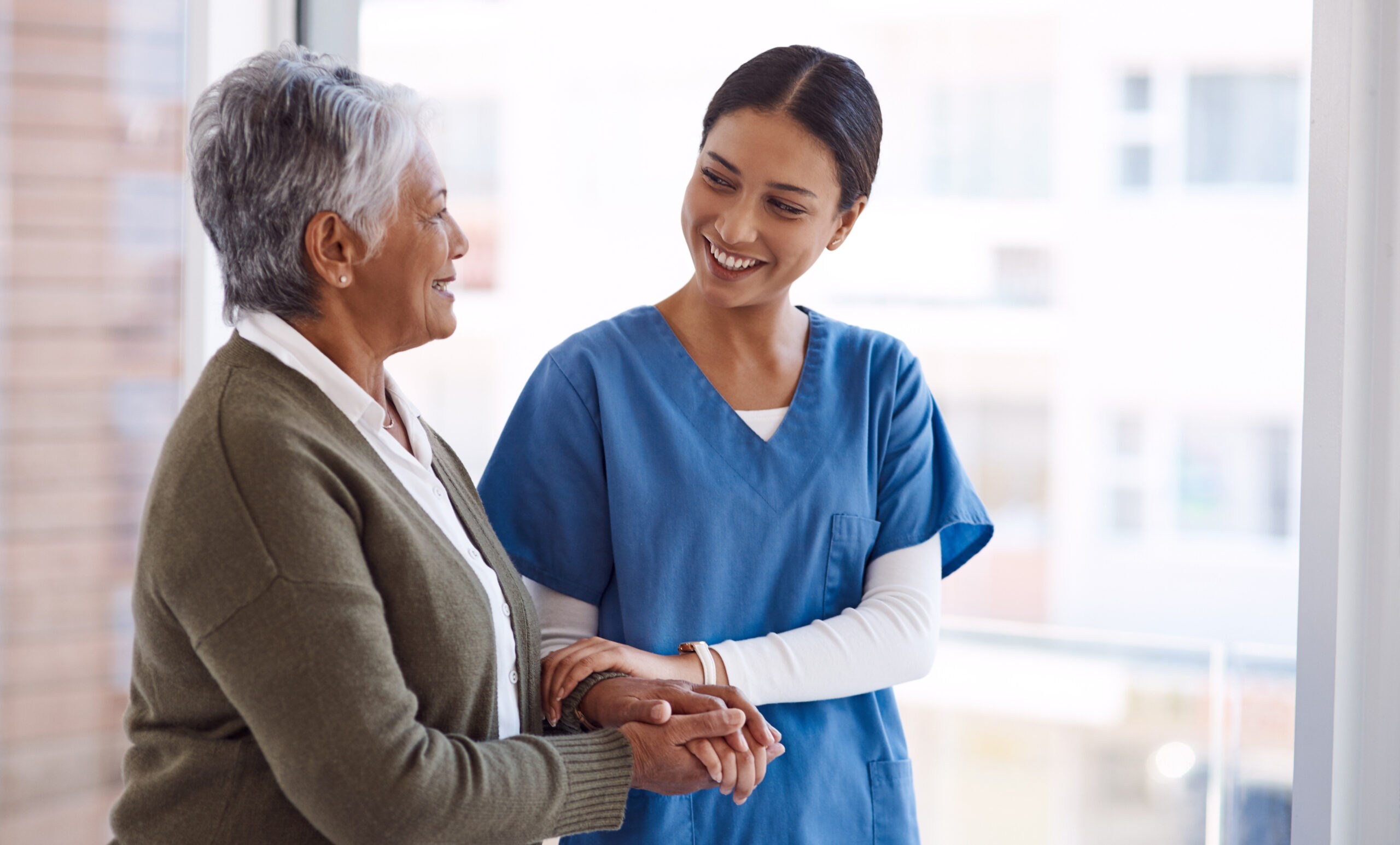 support caregiver with senior woman holding hands